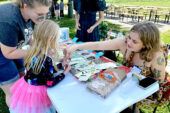 Photo of a girl in a pink tutu standing at a table and holding a seedball.