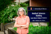 Dr. Rosencranz stands outdoors in front of a sign for the Carle Illinois College of Medicine