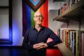 Stefan Vogler standing in front of a Pride flag