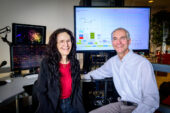 Portrait of researchers in a laboratory. They are sitting in front of two computer monitors displaying data and visualizations of their experiments.