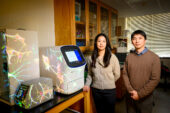 Two researchers stand next to equipment onto which an image of neuron scans is projected in the Tsai Lab at Burrill Hall.