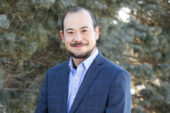 Professor Makoto Inoue stands outside wearing a dark grey suit.