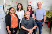 The research team sits and stands together as a group in a research setting.