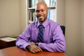 Photo of social work professor Ryan Wade seated at the desk in his office