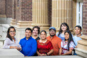Group photo of several people standing outside a brick building with columns in the background.