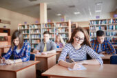 High school students sitting at their desks and writing on test papers