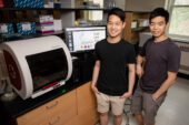 Timothy Tana dn Nicholas Wu stand in a laboratory.