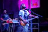 AJ Ghent onstage, singing and playing guitar.