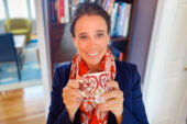 Professor M. Yanina Pepino seated in her home holding a cup of coffee. A bookcase with books is behind her.