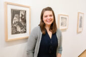 Curator Kathryn Koca Polite stands in front of a gallery wall hung with WPA prints.