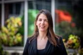Portrait of Jessica Brinkworth, standing facing the camera and smiling. She is outdoors on the U. of I. campus.