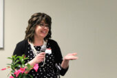 Penny Nigh holds a microphone and gestures