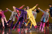 Dancers frozen in midair wearing colorful costumes.