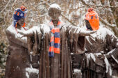 Sculpture of a woman wearing a scarf and two men wearing hats.
