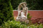 A stone sculpture of a girl holding a scarf
