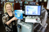 Sue Steinfeldt, the assistant director of course technology, shows off a finished book in front of the Espresso Book Machine, located on the second floor of the Illini Union Bookstore.