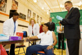 Illinois women's basketball coach Jolette Law (seated) prepares to receive the seasonal flu vaccine.
