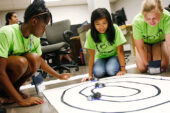 Campers in the robotics camp test small electric cars that they built and programmed. The cars are optically guided, so they are programmed to follow the black lines of tape.