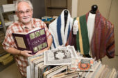 Gilbert Witte poses with some of the thousands of items included in the collection of needlecraft books and ephemera he donated to the University of Illinois Library.