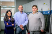 A woman and two men stand in a lab.