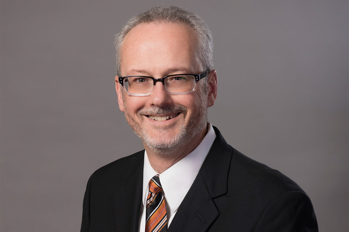 Professor John M. Murphy wearing a dark suit, white shirt and tie