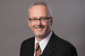 Professor John M. Murphy wearing a dark suit, white shirt and tie