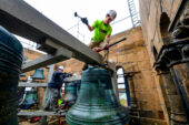 A man standing on top of one of the bells during removal.