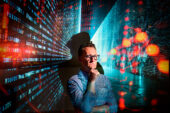 Photo of John Schwenkler surrounded by screens showing digital data.
