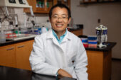 A veterinarian in a white coat sits in a lab.
