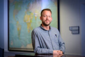 Portrait of Fogelman in front of a world map.