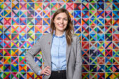 Professor Kaylin Ratner standing in front of a multicolored background