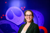 A woman stands in front a mural depicting viruses and cells