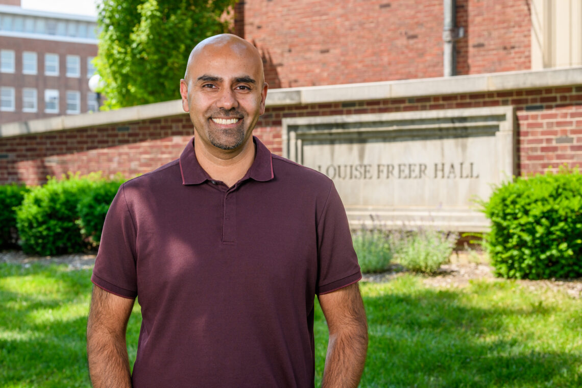 Portrait of Naiman Khan standing outside in front of Freer Hall on the U. of I. campus.