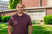 Portrait of Naiman Khan standing outside in front of Freer Hall on the U. of I. campus.