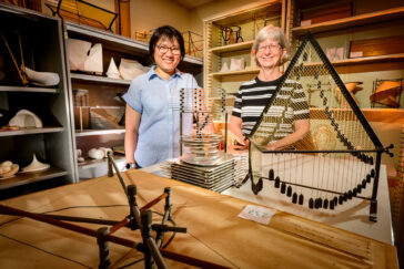Sarah Park and Karen Mortensen are seen surrounded by mathematical models, including an aluminum tower of cascading circles and a model featuring criss-crossing strings in a frame.