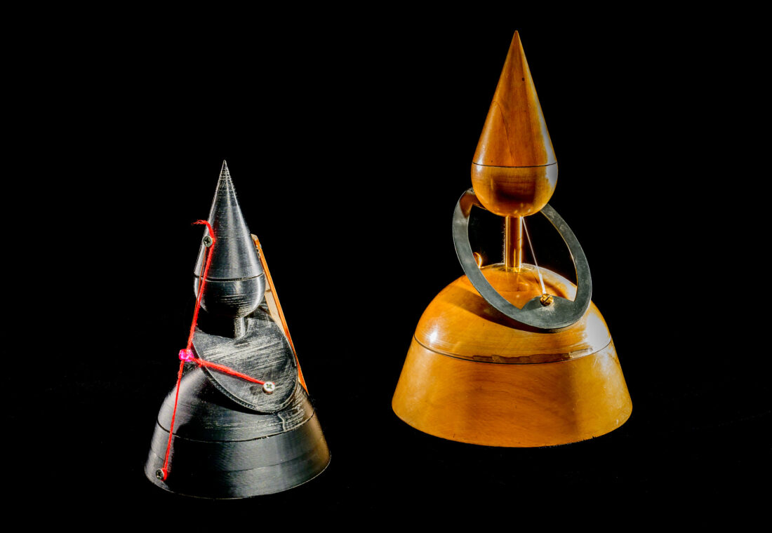 Photo of two identical mathematical models featuring a portion of a cone that, when sliced, is an ellipse.