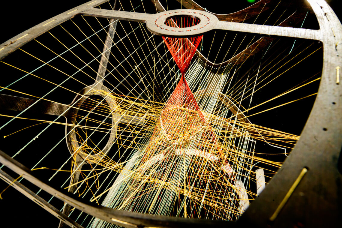 Photo of the interior of a model with different colored strings attached to a frame.