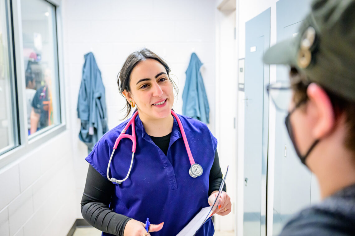 Photo of a smiling Dr. Valbuena and the profile of someone she's talking to in the hallway of the clinic. 