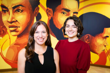 Social work professor Tara Powell and graduate student Jenna Muller standing in front of a mural of Black young people.