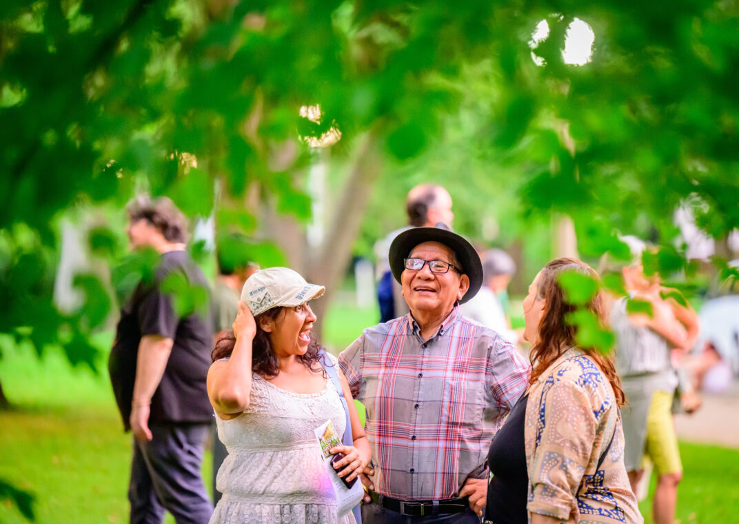 Photo of three people laughing together in a park.