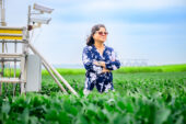 Photo of Madhu Khanna standing in a soybean field next to CO2 monitoring equipment.