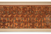 Image of a fragment of a woman's dress in orange and rust tones, with Andean images of birds and of people wearing headdresses.