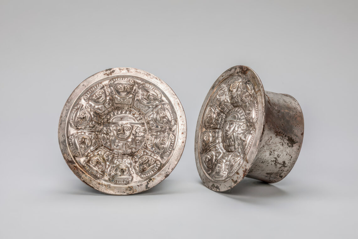 Photo of silver, intricately decorated Chimu ear spools from Peru.