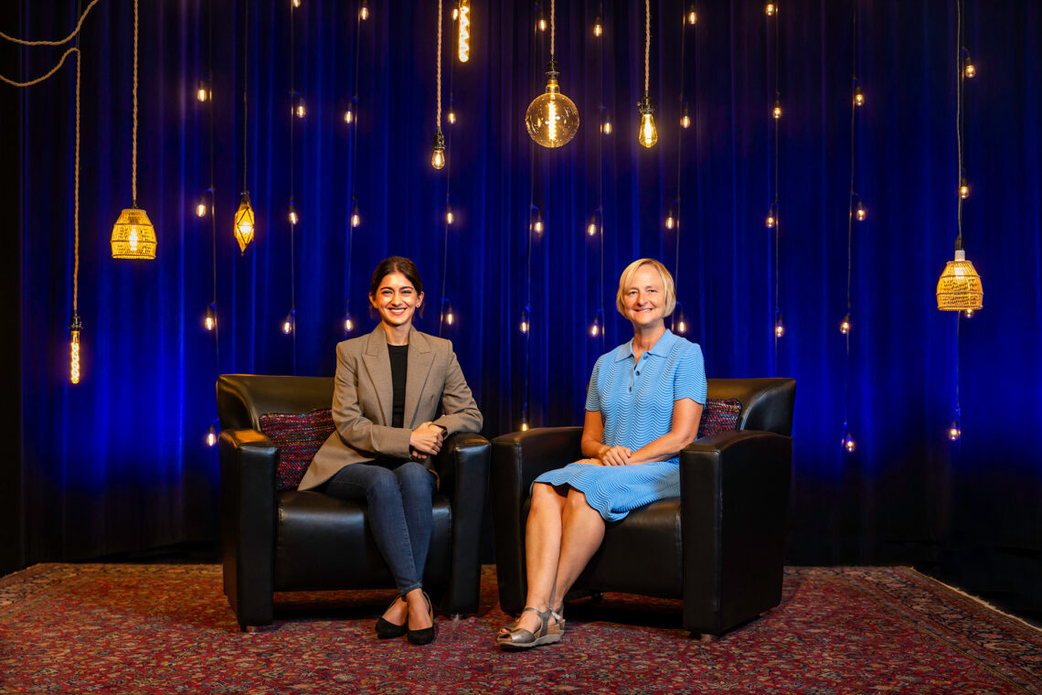 Sakshi Bhalla and Michelle Nelson sitting before a blue background