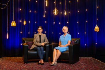Sakshi Bhalla and Michelle Nelson sitting before a blue background