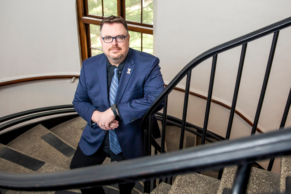 Photo of Jacob Pinholster leaning on the banister of a circular staircase in the Architecture Building.