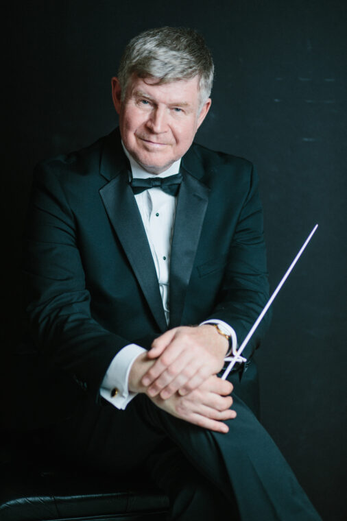 Photo of Ian Hobson dressed in a tuxedo and holding a conductor's baton.