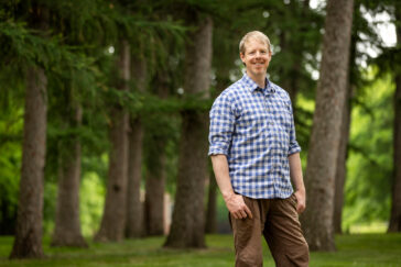 Photo of the researcher standing in front of a woodland.