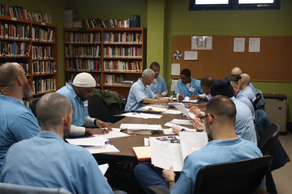 Students in the pilot program to work with high school students seated around a table.