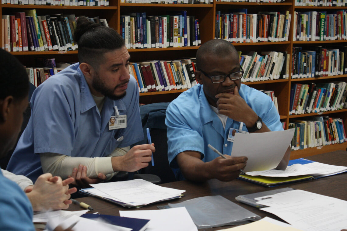 Students seated at a table reading documents.